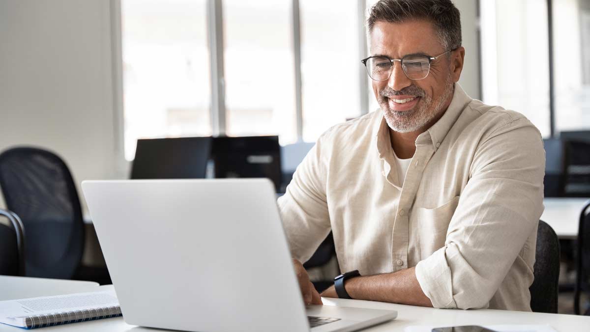 Smiling businessman looking at laptop on desk