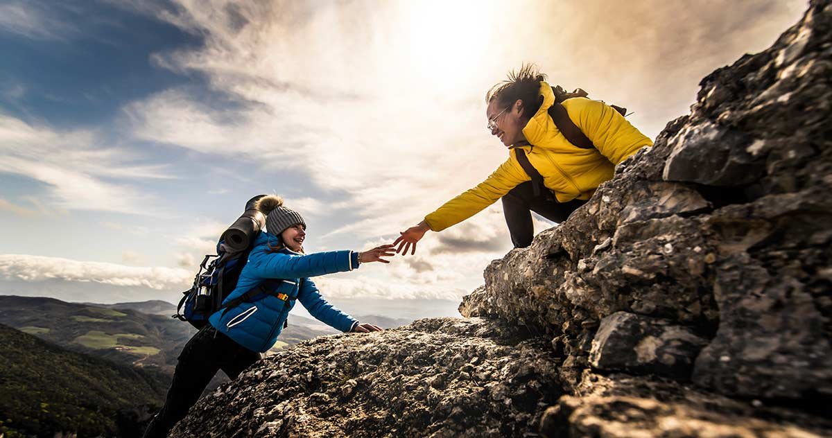 One person helping another mountain climbing