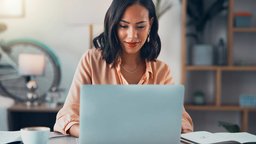 Smiling woman at desk working on laptop